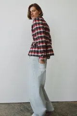 Blazer Zara Woman Collection de corte entallado con bajo peplum, confeccionada en tejido de mezcla de algodón con estampado de cuadros en tonos rojo, azul marino y blanco. Presenta cuello solapa, manga larga, bolsillos delanteros y cierre frontal con botones metálicos en relieve.