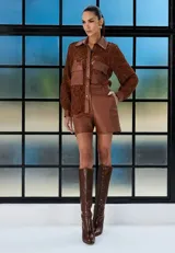 Camisa de cuero marrón con mangas de encaje al tono, cuello clásico, cierre frontal con botones y bolsillos delanteros con solapa.
