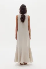 Vestido largo de lino color beige, sin mangas, con cuello redondo y diseño ajustado que se ensancha en la parte inferior con godets que aportan movimiento al ruedo.