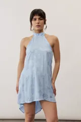 Top halter celeste con diseño asimétrico de corte más largo en la parte trasera, cuello alto y sutil estampado floral.