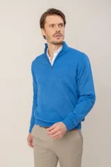 Sweater de punto en lana merino, color azul, con cuello alto y cierre frontal parcial. Presenta puños y ruedo acanalados.