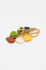 Llavero de metal dorado con mosquetón y argolla, decorado con múltiples dijes de corazones de resina en colores verde, naranja, amarillo, blanco y azul oscuro, y cuenta con un abalorio central esférico dorado con el logotipo de la marca grabado.