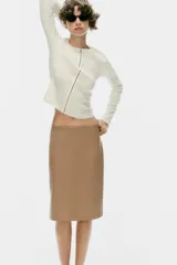 Falda midi de tiro medio confeccionada en tejido efecto piel de color marrón, con costura central frontal y cierre lateral con cremallera oculta.