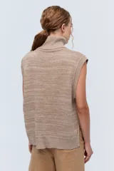 Chaleco de punto azul con cuello alto y diseño de trenzas.