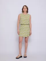 Falda corta con estampado floral en tonos verde lima y blanco, con cintura elástica y corte asimétrico en el ruedo.