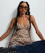 Vestido corto de corte godê confeccionado en tejido de tule con estampado animal print de leopardo. Presenta breteles finos, escote en V y diseño fluido con forro interno.