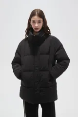 Campera puffer negra de corte holgado, con cuello alto, cierre frontal oculto y bolsillos laterales.