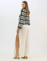 Cardigan abierto de tejido de punto calado con diseño geométrico y floral bicolor. Presenta escote en V, mangas largas y cierre frontal con tiras para anudar. Incluye detalles de vivos a contraste en el contorno del escote, puños y ruedo.