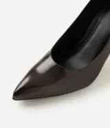 Zapato tipo scarpin de color marrón oscuro, confeccionado en poliuretano con acabado liso. Presenta un diseño clásico con punta fina y taco fino de altura media.