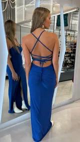 Vestido largo azul con brillo, de corte ajustado, escote en V con frunce en el centro, tirantes finos, tajo lateral en la pierna y espalda descubierta con tiras cruzadas.