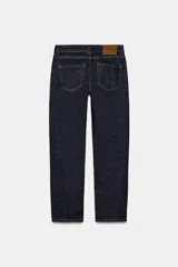 Jeans de tiro medio con corte slim leg, confeccionados en denim color beige. Presentan cintura con trabillas, diseño clásico de cinco bolsillos y cierre frontal con cremallera y botón metálico.