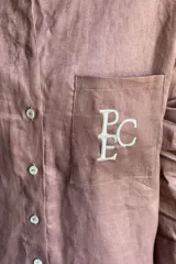 Camisa de lino color gris claro con bordado de monograma PEC en el bolsillo.