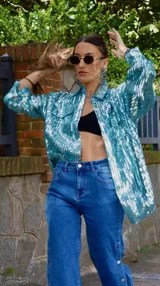 Chaqueta celeste con lentejuelas, corte tipo camisa, de manga larga y con bolsillos frontales.