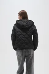 Campera acolchada de color beige con diseño capitoneado en forma de rombos, cierre frontal completo y capucha integrada.