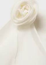 Top blanco de tirantes finos con escote drapeado y detalle de flor en el hombro.