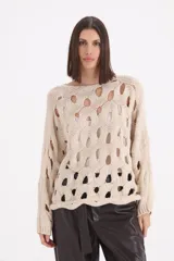 Sweater de punto color beige con diseño de calados circulares en toda la prenda, cuello redondo y mangas largas con puños acanalados.