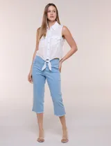 Capri blanco de corte ajustado, con tiro alto y pretina ancha elastizada tipo faja. Presenta bolsillos falsos al frente con remaches, piernas entalladas con pequeñas aberturas en los laterales y ruedo desflecado.