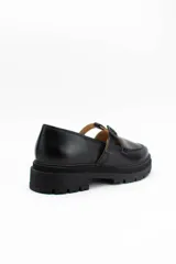 Mocasines estilo Mary Jane con diseño de estampado de vaca (cow print), confeccionados en cuero. Presentan una tira con hebilla ajustable sobre el empeine y una suela track negra de 4,5 cm de altura.