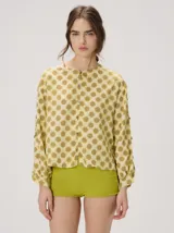 Camisa voluminosa de algodón con mangas amplias y abullonadas que se ajustan en los puños. Tiene calce suelto, hombro caído, cuello redondo y cierre frontal con botones. Presenta estampado geométrico en tonos mostaza y beige.