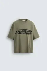 Camiseta de algodón con corte relajado, cuello redondo y manga corta. Presenta un estampado gráfico frontal en color negro con tipografía estilo deportivo y efecto desgastado.