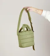 Bolsito tipo tote acolchado de color verde oliva, con diseño impermeable, doble asa de mano y correa larga ajustable y extraíble. Cuenta con cierre superior y el logo de la marca estampado en el frente.