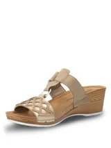 Sandalias de plataforma baja con diseño de tiras cruzadas en color beige y dorado. Presentan una tira superior con cierre de velcro y una tira frontal con detalle de calados geométricos y pequeñas tachas metálicas. La plantilla es acolchada y la suela tiene textura tipo yute.