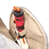 Mochila deportiva color gris, confeccionada en material textil con acabado arrugado. Presenta compartimento principal con cierre doble, bolsillo frontal con logo circular, compartimento inferior independiente para calzado y bolsillos laterales. Incluye tirantes ergonómicos ajustables y espaldera acolchada con malla transpirable.
