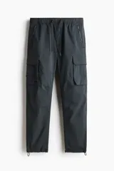 Pantalón cargo gris oscuro de nylon con corte estándar, cintura elástica con cordón ajustable, bolsillos con cierre en los laterales y bolsillos de parche con solapa en las piernas.