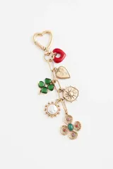 Llavero de metal dorado con mosquetón en forma de corazón y múltiples dijes colgantes: un corazón esmaltado rojo, un corazón texturizado con cristales, un trébol de cuatro hojas verde, un dije circular con diseño de sol, un dije con perla central y un dije floral con detalles de piedras de colores.