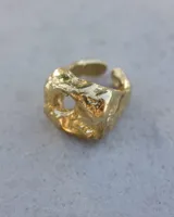 Anillo dorado con forma irregular y un agujero en el centro.
