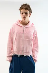 Campera con capucha de tejido texturizado en color rosa claro, de calce relajado. Presenta cierre frontal completo con tirador en forma de aro, bolsillos tipo canguro y logo en relieve del mismo tono en el pecho. Terminaciones con puños y ruedo de borde sin rematar.