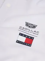 Chomba de piqué color blanco, de corte regular, con cuello y puños de punto canalé. Presenta cierre frontal de tres botones y logo bordado en el pecho de la colaboración entre Tommy Hilfiger y Cadillac Formula 1 Team.