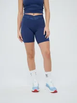 Calza corta tipo biker Umbro para mujer, de color azul marino, con cintura cruzada en V y elástico personalizado con la marca.