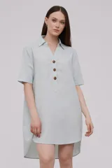 Vestido corto tipo túnica color celeste, de lino, con cuello camisero, mangas cortas y cierre frontal con botones de madera.
