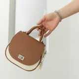 Cartera bandolera de cuero color marrón con asa corta superior y correa larga ajustable.