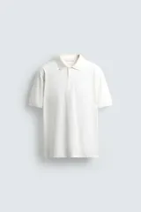 Polo de hombre color blanco hueso, de corte regular fit, con cuello solapa y tapeta de dos botones. Manga corta terminada en rib.