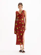 Vestido largo al tobillo confeccionado en seda de color rojo con estampado de limones y peras. Posee escote buche, diseño sin mangas, tajos laterales y detalle de tiras colgantes en el hombro.
