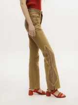 Pantalón de denim color tostado con tiro alto y corte oxford. Presenta detalles de apliques metalizados a lo largo de las costuras laterales y en los bolsillos.