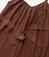 Mono largo de viscosa color marrón, con escote redondo fruncido, tirantes finos y cintura ajustable con lazo del mismo tejido. Presenta un corte holgado y fluido en las piernas.