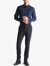 Camisa de vestir azul marino de manga larga, con cuello clásico y cierre con botones. Presenta un logo bordado en el pecho. Corte entallado.