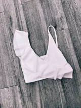 Top de bikini fucsia con un solo tirante y volados en el escote.