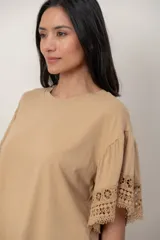Remera de algodón color blanco, con cuello redondo y mangas cortas holgadas que presentan detalles de encaje broderie.