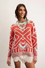 Buzo oversize de punto color marfil con diseño geométrico jacquard en tonos rosado, amarillo, celeste y marrón. Cuenta con cuello redondo y mangas largas.