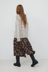 Falda midi de corte irregular con diseño a cuadros en tonos marrones, negros y beige. Presenta una silueta acampanada con caída fluida.