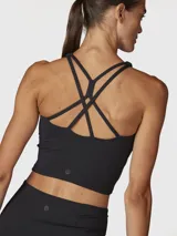 Top deportivo de sujeción media, color negro, con diseño de cuello alto y espalda cruzada. Confeccionado con tecnología Aloe Vera para mayor suavidad.