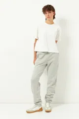 Pantalón de jogging gris claro, de corte holgado, con cintura y tobillos elastizados, y bolsillos laterales.