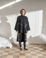 Capa negra de paño de lana con cuello mao y cierre frontal con ganchos ocultos. Estampado serigráfico negro brillante en cuerpo y cuello.