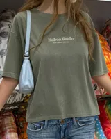 Remera oversize negra con diseño gráfico en la espalda que incluye la inscripción "Kaboa Radio" y un personaje ilustrado, de corte amplio y mangas cortas.