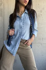 Camisa celeste de manga larga con bordados geométricos frontales a lo largo de la botonadura, cuello camisero clásico y cierre frontal de botones.