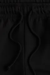 Jogging negro de felpa con interior cepillado suave, cintura elástica fruncida con cordón ajustable y puños elásticos en los bajos.